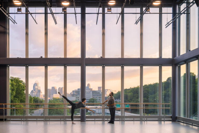 Picture of two ballet dancers practicing in front of glass windows of a rehearsal studio at the Valentine Center for Dance.